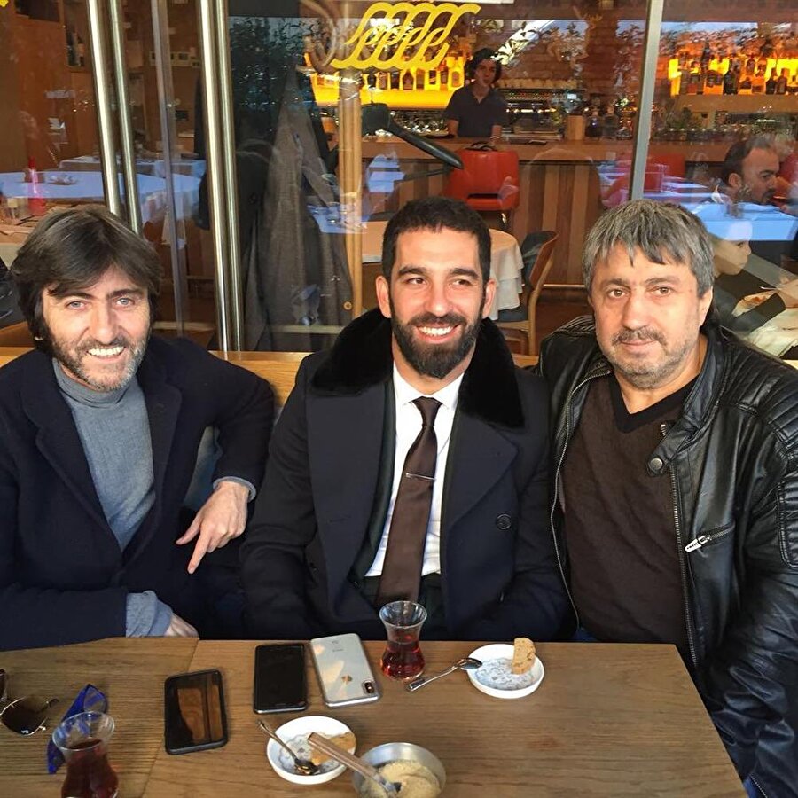 Rıdvan Dilmen ve Arda Turan fanatik bir futbolseverin isteğini kırmayarak fotoğraf çektiriyor.