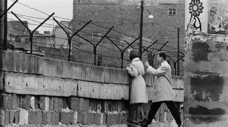 Özgürlük sesleri
Doğu Almanya'da insanlar özgürlük için 1989'un yaz aylarında sokaklara çıktı. Bu gösterilerin yanı sıra çok sayıda kişi Prag, Varşova ve Budapeşte'deki Alman büyükelçiliklerine başvuruda bulunarak Batı Almanya'ya gitmeye çalışıyordu. Bu gelişmeler Doğu Almanya hükümetini seyahat düzenlemesi yapmaya zorladı. Doğu Almanya'yı yöneten Sosyalist Birlik Partisi (SED) Sözcüsü Günter Schabowski, 9 Kasım akşamı düzenlediği basın toplantısında hükümetin yürürlüğe koyacağı seyahat düzenlemesini okudu.