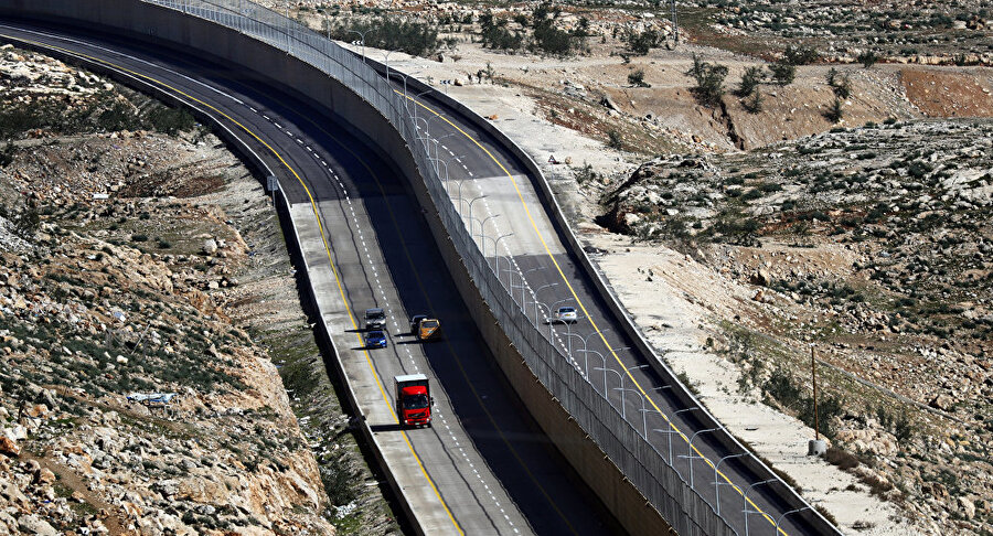 İsrail Batı Şeria'da "Utanç Yolu"nu açıyor
İsrail tarafından açılan yeni otoyol, İsrail vatandaşları tarafından memnuniyetle karşılanırken, Filistinlilerin tepkisini üzerine çekti. "Utanç Yolu" olarak tanımlanan bu yol, İsrail vatandaşları ve Filistinlilerin kullanacağı yolları ayırmak için tasarlandı. Yolun kullanıma hazır ilk bölümü Kudüs bölgesine ulaşımı sağlıyor ancak bunu yaparken İsrailli ve Filistinliler için iki farklı güzergah oluşturuyor. Yol, İsrailli vatandaşlar için kontrol noktalarından kaçınarak doğrudan Kudüs'e varmayı olanaklı kılarken, Filistin vatandaşlarını ise kontrol noktalarına yönlendiriyor.