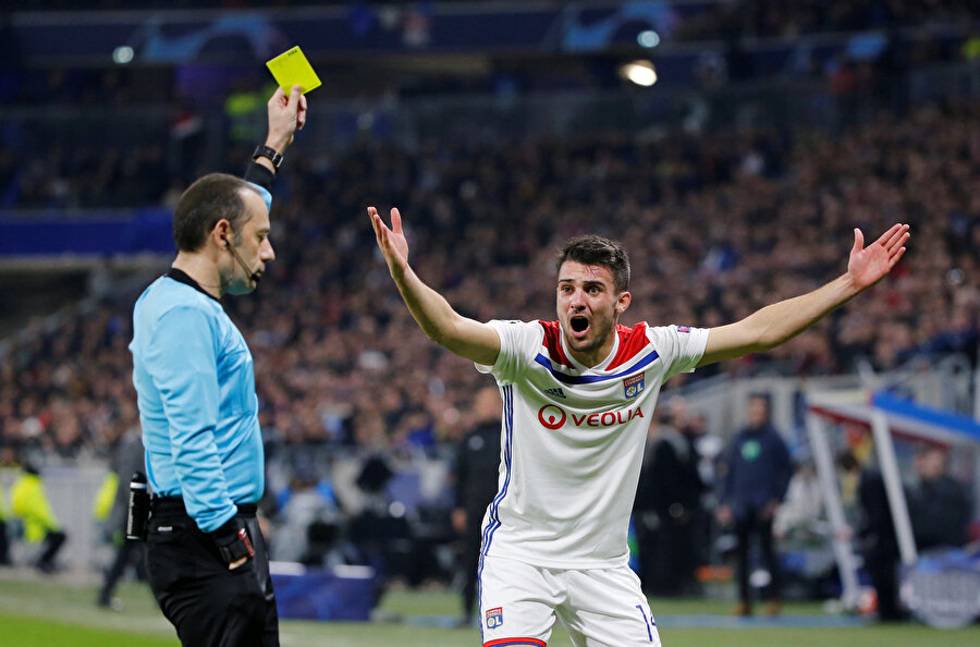 Cüneyt Çakır, Lyon forması giyen Leo Dubois'ye sarı kart gösteriyor.