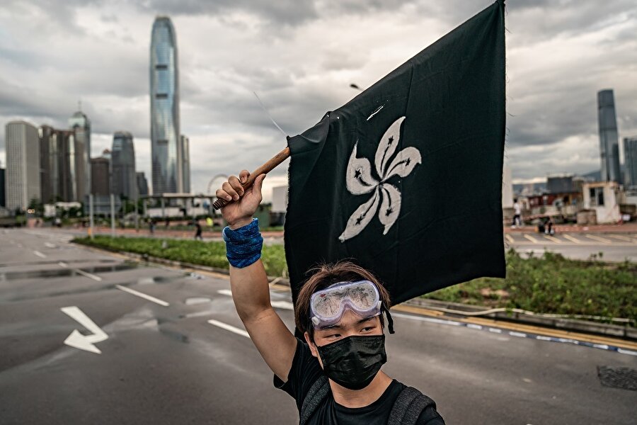 Bir protestocu Hong Kong bayrağının siyah bir versiyonunu sallıyor.
