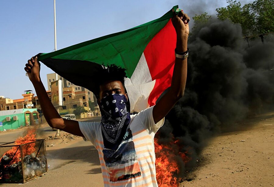 Sudan Başsavcılığı bünyesindeki 3 Haziran olaylarını Araştırma Komisyonu'nun raporunu protesto etmek için düzenlenen gösteriler sırasında Sudan bayrağı açan bir gösterici.