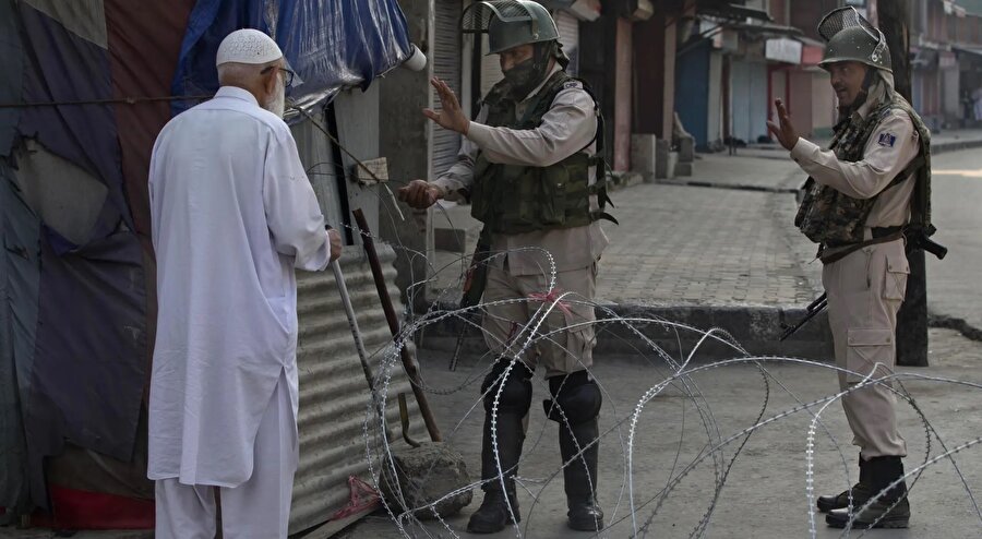 Keşmir'in özel statüsünün kaldırılmasının ardından güvenlik önlemlerinin sıkılaştırıldığı Srinagar'da kontrol noktasında yaşlı bir adamı durduran Hindistan güçleri.