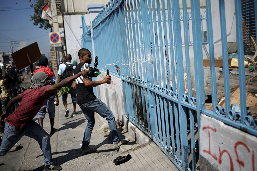 Haiti

                                    
                                    Kıtanın en fakir ülkesi Haiti'de en az 48 kişinin öldüğü protestolar, akaryakıt, içme suyu ve gıda temininin imkansız hale gelmesi, ekonomik daralma neticesinde küçük işletmelerin kredi bulamaması ve Devlet Başkanı Jovenel Moise'nin (Venezuela eski Devlet Başkanı Hugo Chavez'in Karayip ülkelerine destek amacıyla ucuz petrol satılması için uygulamaya koyduğu) "PetroCaribe" projesindeki fonlarda yapılan ve 4 milyar doları bulan yolsuzluk iddialarında adı geçmesi gibi nedenlere dayanıyor. 
Şubatın ilk haftasında başlayan ilk dalga protesto ve şiddet olaylarında, Amerikalılar Arası İnsan Hakları Komisyonunun (IACHR) paylaştığı verilere göre, 26 kişi öldü, 80 kişi yaralandı. İkinci dalgası 9 Temmuz'da başlayan olaylarda ise 2 kişi hayatını kaybetti.Başkent Port-au-Prince'de özellikle fakirlerin yoğun katılım gösterdiği protestolarda 7. haftasına giren son dalga ise 16 Eylül'de başladı ve şu ana kadar geride biri gazeteci en az 20 ölü ile 200'e yakın yaralı bıraktı.
                                
                                