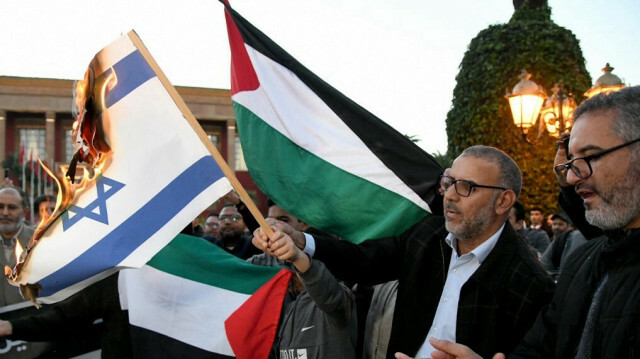 Des Marocains brûlent le drapeau israélien alors qu'ils se rassemblent pour protester contre la normalisation des relations avec Israël, devant le bâtiment du parlement à Rabat, la capitale, le 24 décembre 2022. @ AFP