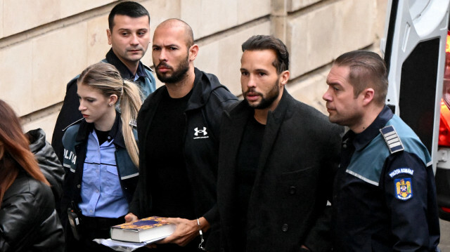 L'ancien kickboxeur professionnel britannico-américain et influenceur controversé Andrew Tate et son frère Tristan Tate arrivent menottés et escortés par la police au palais de justice de Bucarest, le 10 janvier 2023. @ DANIEL MIHAILESCU / AFP