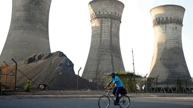 Un cycliste passe devant une tour de refroidissement dans une usine locale à Bulawayo, au Zimbabwe, le 20 août 2019. @ REUTERS/Philimon Bulawayo