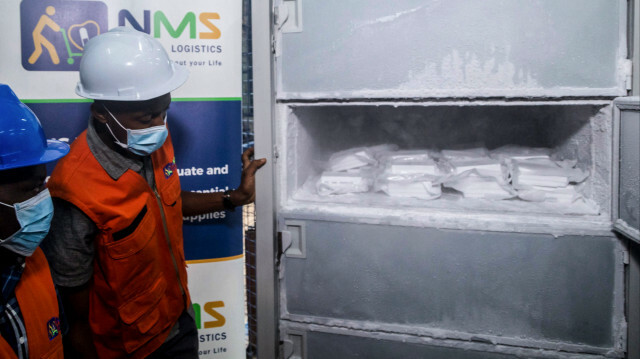 Des opérateurs regardent 1200 doses nouvellement arrivées de vaccin d'essai Ebola dans le réfrigérateur à ultra basse température des magasins médicaux nationaux à Entebbe le 08 décembre 2022.
@Badru KATUMBA / AFP 