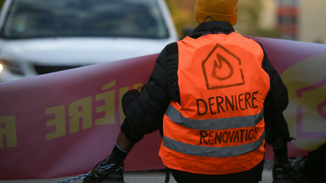 Un militant écologiste du groupe « Dernière rénovation » tient une banderole alors que les membres du groupe bloquent le trafic pour réclamer des rénovations de bâtiments énergétiques en France, à Toulouse, dans le sud-ouest de la France, le 24 novembre 2022. @ VALENTINE CHAPUIS / AFP