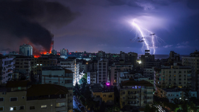 Des éclairs zèbrent le ciel au-dessus de la ville de Gaza, tandis que des volutes de fumée s'élèvent à la suite d'une frappe aérienne israélienne, le 9 octobre 2023. Crédit photo: MOHAMMED ABED / AFP