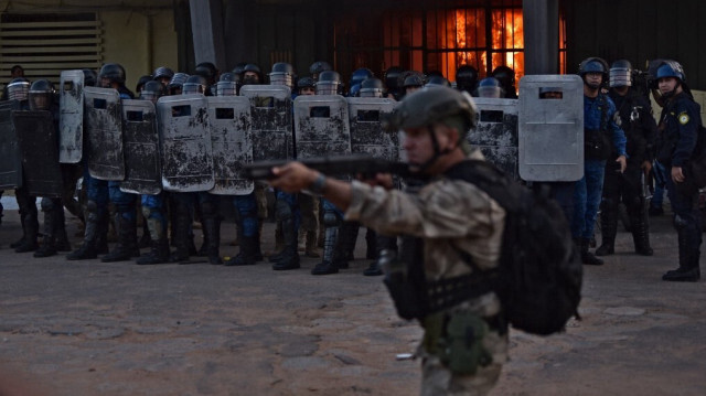 Les forces de sécurité montent la garde alors qu'un incendie brûle à l'intérieur de la prison de Tacumbu après que des centaines de détenus aient pris possession de l'établissement, à Asuncion, le 10 octobre 2023. Crédit Photo: NORBERTO DUARTE / AFP