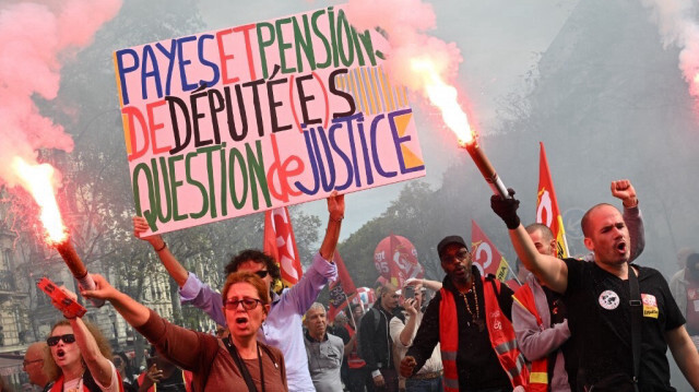 Des manifestants brandissent des fumigènes lors de la mobilisation appelée par les intersyndicales de France, à Paris, le 13 octobre. Crédit photo: BERTRAND GUAY / AFP
