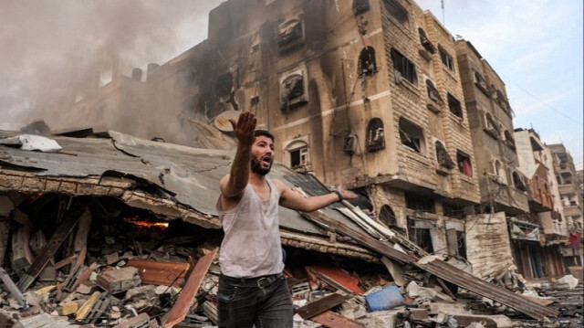 Un homme réagit à l'extérieur d'un bâtiment effondré en flammes suite à un bombardement israélien dans la ville de Gaza le 11 octobre 2023. Crédit photo: MOHAMMED ABED / AFP