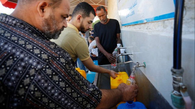 Des Palestiniens remplissent des bouteilles d'eau potable provenant d'un distributeur alors que la pénurie d'eau potable sévit suite à la suspension de l'alimentation en eau depuis Israël vers Gaza, le 15 octobre 2023. Crédit photo: AA