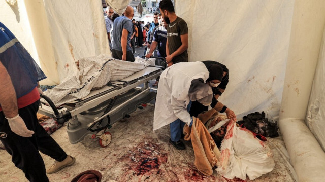Des personnes inspectent l'identification d'un des corps des victimes de l'explosion de nuit à l'hôpital Ahli Arab dans une tente de fortune sur le site dans le centre de Gaza le 18 octobre 2023. Crédit Photo: MAHMUD HAMS / AFP.