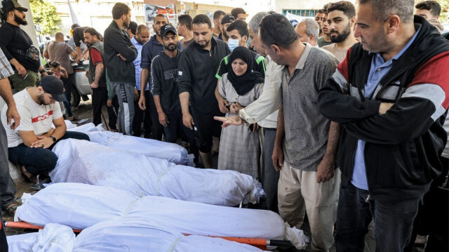 Des personnes se rassemblent près des corps enveloppés des victimes qui ont péri dans les bombardements israéliens de l'hôpital Ahli Arab dans le centre de Gaza, le 18 octobre 2023. Crédit Photo: Mahmud HAMS / AFP