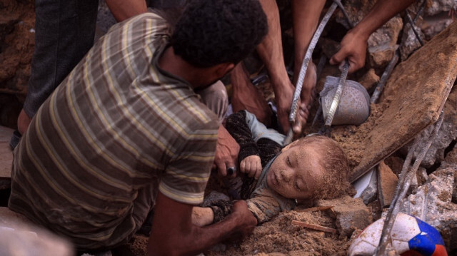 Des Palestiniens essaient d'extirper le corps d'un enfant des décombres d'un bâtiment dans le camp de réfugiés de Nuseirat, à Gaza, le 31 octobre 2023, alors qu'Israël bombarde sans relâche l'enclave palestinienne. Crédit photo: MAHMUD HAMS / AFP
