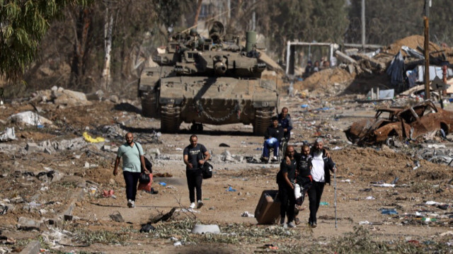 Des Palestiniens traversent la route de Salaheddine dans le district de Zeitoun, à Gaza, en passant devant les chars de l'armée d'occupation israélienne, le 24 novembre 2023. Crédit photo: MAHMUD HAMS / AFP
