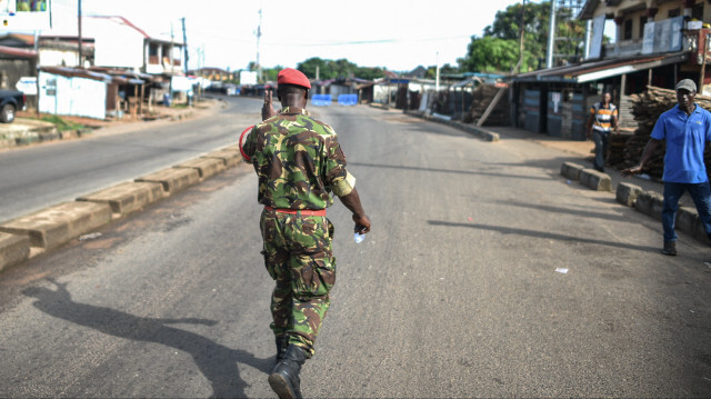 Un soldat de la police militaire sierra-léonaise saluant un homme le long d'une route déserte à Freetown, le 26 novembre 2023. Crédit Photo: Saidu BAH / AFP

