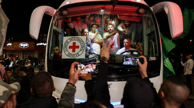 Un bus transportant du personnel de la Croix-Rouge et des prisonniers palestiniens libérés des prisons israéliennes en échange d'otages libérés par le Hamas dans la bande de Gaza, traversant des supporters brandissant des drapeaux à Ramallah, en Cisjordanie occupée, le 26 novembre 2023. Crédit Photo: AHMAD GHARABLI / AFP

