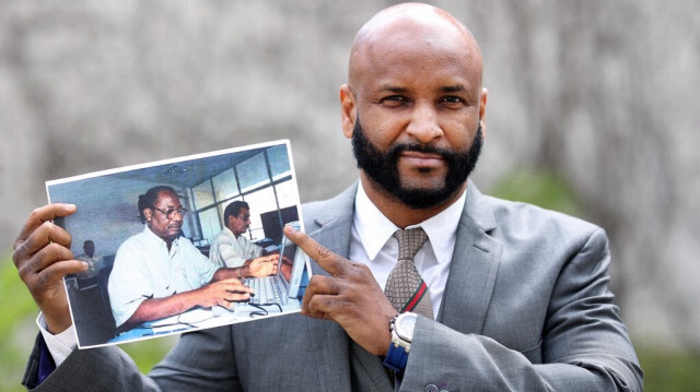 Baba Hydara, fils de feu Deyda Hydara, pose avec une photo de son père en marge du procès contre l'accusé Gambien Bai L. Crédit photo: Ronny Hartmann / AFP