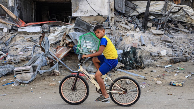 Un enfant palestinien sauve son oiseau à vélo des bâtiments détruits par les frappes israéliens, à Rafah, dans le sud de la bande de Gaza, le 6 novembre 2023. Crédit photo: SAID KHATIB / AFP
