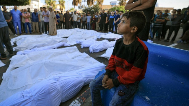 Un enfant palestinien assis aux côtés des défunts tués par les bombardements israéliens, à Deir el-Balah, dans le centre de la bande de Gaza, le 6 novembre 2023. Crédit photo: MAHMUD HAMS / AFP
