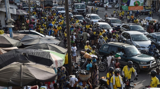Les automobilistes et les motocycles de taxi roulent dans une impasse dans un environnement de marché à Cotonou, le 14 avril 2021.