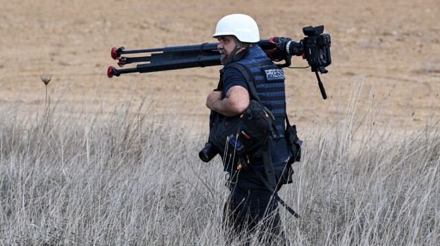 Le journaliste de l'AFPTV Nicolas Garcia Ferrari se déplace avec une caméra sur un trépied près de la bande de Gaza, le 12 octobre 2023.