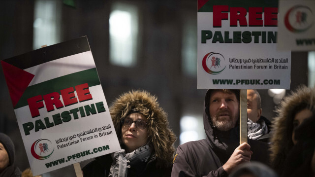 Des manifestants brandissent des banderoles en soutien aux enfants palestiniens tués à Gaza par l'armée d'occupation israélienne, lors d'une veillée devant le bureau du Premier ministre britannique, le numéro 10, à Londres, le 13 décembre 2023.

