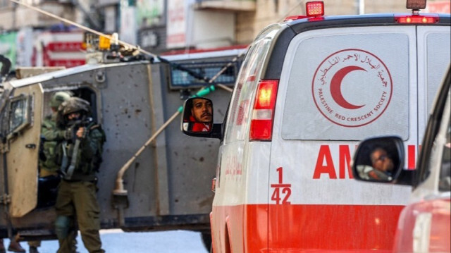 Un militaire de l'armée d'occupation pointe son arme sur des ambulances du Croissant-Rouge Palestinien, qui attendent de passer pour se rendre à l'hôpital en Palestine occupée, le 13 décembre 2023.