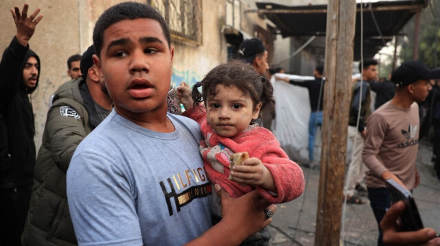 Un jeune Palestinien porte une petite fille blessée suite à un bombardement de l'armée d'occupation israélienne à Rafah, dans la bande de Gaza, le 12 décembre 2023.