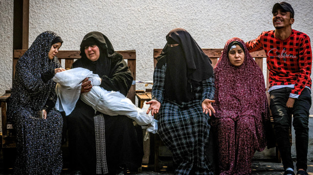 Une femme de la famille palestinienne Ashour tient le corps d'un bébé alors que d'autres pleurent, le 14 décembre 2023, à l'hôpital Najar à Rafah, dans le sud de la bande de Gaza.