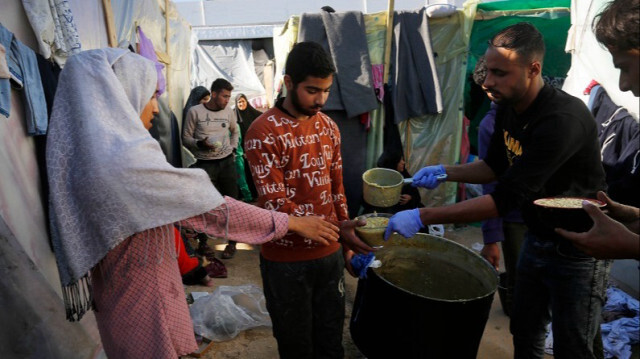 Des Palestiniens déplacés, vivant dans des tentes dans un camp de la ville de Deir Al Balah, luttant avec des ressources limitées et des conditions difficiles, attendent de recevoir de la soupe distribuée par des bénévoles à Gaza, le 16 décembre 2023