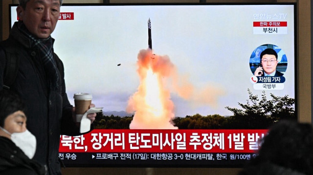 Une femme passe devant un écran de télévision diffusant un journal télévisé avec des images d'archives d'un essai de missile nord-coréen, dans une gare de Séoul, le 18 décembre 2023.