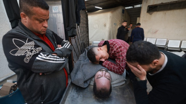 Des Palestiniens en deuil devant le corps d'un Palestinien de la famille Harb tué par les bombardements de l'armée d'occupation israélienne, dont trois enfants de la même famille, à l'hôpital al-Najjar de Rafah, dans le sud de la bande de Gaza, le 12 décembre 2023.