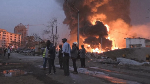 Les gens devant les flammes de l'incendie du principal dépôt de carburant de Conakry en Guinée, le 18 décembre 2023.