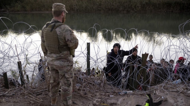 Un migrant vénézuélien demande à un garde national du Texas de lui indiquer la direction d'un centre de traitement après avoir traversé le Mexique pour se rendre aux États-Unis, le 17 décembre 2023 à Eagle Pass, au Texas.