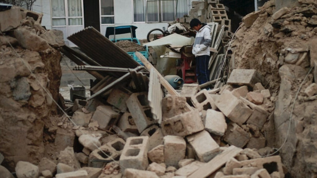 Un garçon se tient parmi les décombres de sa maison effondrée à Dahejia, dans la province du Gansu, dans le nord-ouest de la Chine, le 20 décembre 2023.