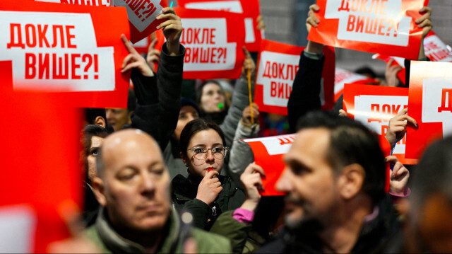 Des manifestants tiennent des pancartes sur lesquelles on peut lire "Combien de temps encore ?" lors d'une manifestation devant le bâtiment de la Commission électorale à Belgrade, le 19 décembre 2023, deux jours après les résultats des élections législatives et locales. 