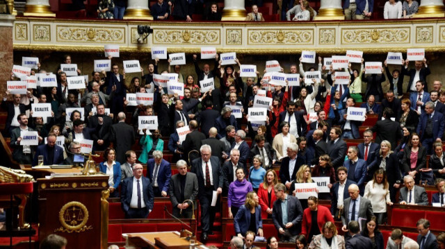 Des députés de gauche NUPES tiennent des pancartes sur lesquelles on peut lire "Liberté", "Égalite", "Fraternité", la devise nationale de la France, après le vote et l'approbation du projet de loi sur l'immigration, à l'Assemblée nationale française, à Paris, le 19 décembre 2023.