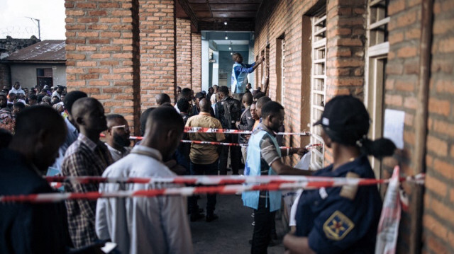 Les responsables de la Commission électorale nationale indépendante (CENI) ont mis en place des pancartes alors que les électeurs font la queue devant le bureau de vote de l'Institut Zanner à Goma en République Démocratique du Congo, le
 20 décembre 2023.