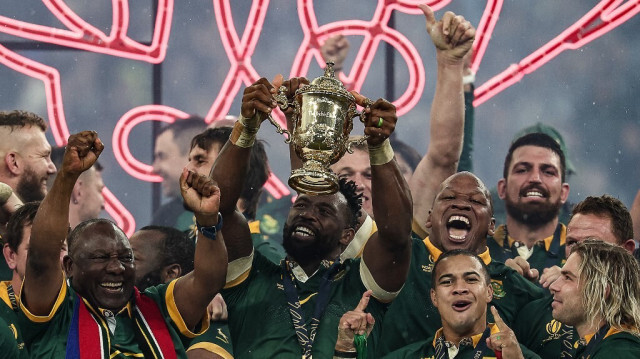 (ARCHIVES) Le flanker et capitaine sud-africain Siya Kolisi (C) soulève la Coupe Webb Ellis, aux côtés du président sud-africain Cyril Ramaphosa (L) et de l'ailier gauche sud-africain Cheslin Kolbe (2e D) ainsi que du demi de mêlée sud-africain Faf de Klerk (D), tandis que les joueurs sud-africains célèbrent leur victoire lors de la finale de la Coupe du Monde de Rugby 2023 contre la Nouvelle-Zélande au Stade de France à Saint-Denis, en périphérie de Paris, le 28 octobre 2023.