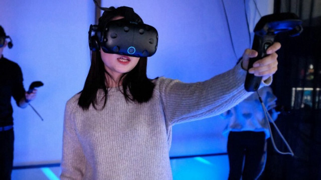 Une femme jouant à un jeu vidéo en utilisant un casque de réalité virtuelle dans une salle d'arcade à Shanghai en Chine, le 13 février 2019.