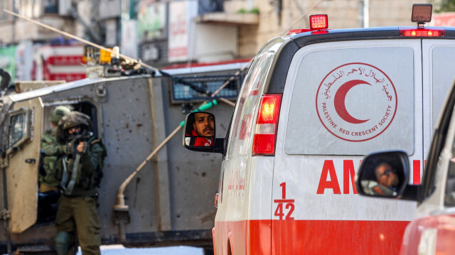 Un soldat israélien pointe son arme alors que des ambulances du Croissant-Rouge palestinien attendent, suite à un raid de l'armée à Jénine en Cisjordanie occupée. 