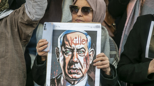 Une manifestante tient le portrait du Premier ministre israélien, Benjamin Netanyahu, qu'elle tient responsable du génocide à Gaza, le 23 décembre 2023.