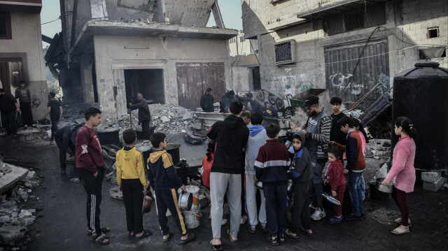 Des enfants palestiniens attendent un repas chaud au milieu des bâtiments résidentiels détruits par l'armée d'occupation ce samedi 23 décembre 2023.