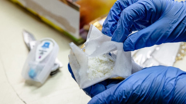 Un agent des douanes présentant de la poudre de cocaïne trouvée dans un colis.