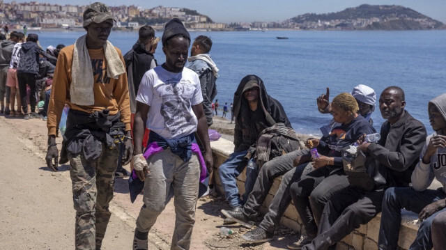 Des migrants subsahariens sont assis sur une merve dans la ville septentrionale de Fnideq au Maroc alors qu'ils tentent de traverser la frontière entre le Maroc et l'enclave nord-africaine espagnole de Ceuta le 19 mai 2021.