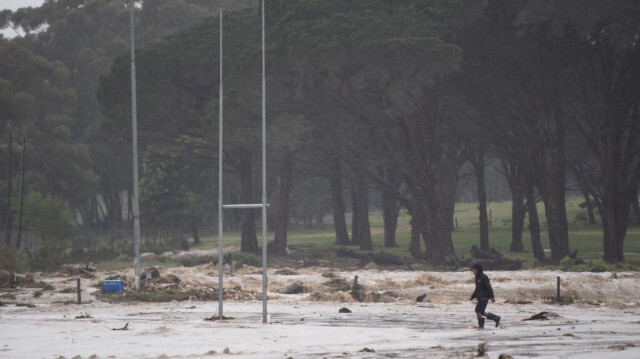 Un homme traverse le terrain de rugby du village lors de fortes inondations à la suite d'une tempête dans le village de Sir Lowry, près de Somerset West en Afrique du Sud, le 25 septembre 2023.